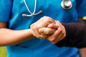 Pflegekraft hält Hand eines Patienten