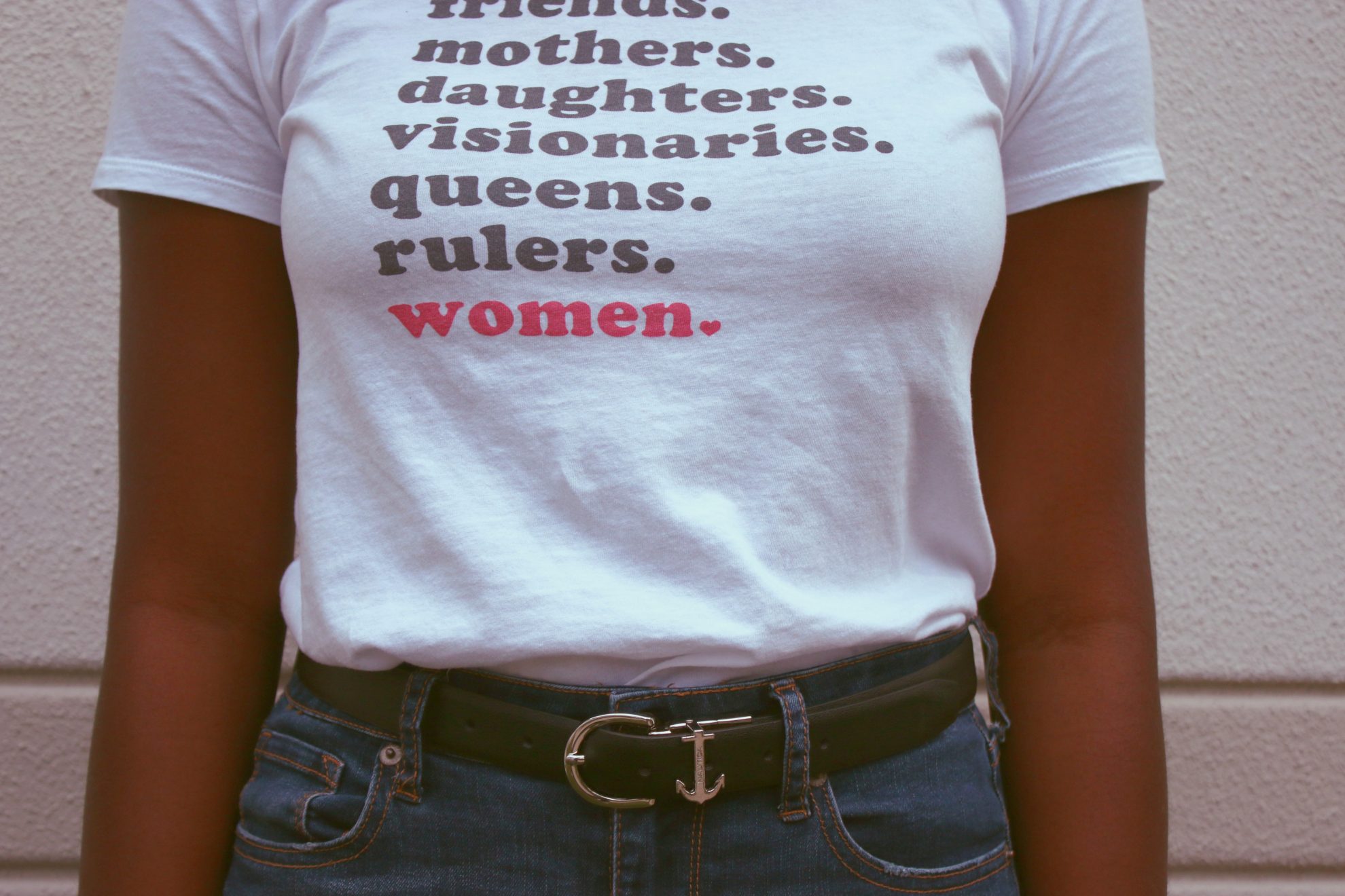 Frau im T-Shirt mit Aufdruck: "Friends. Mothers. Daughter. Visionaries. Queens. Rulers. Women."
